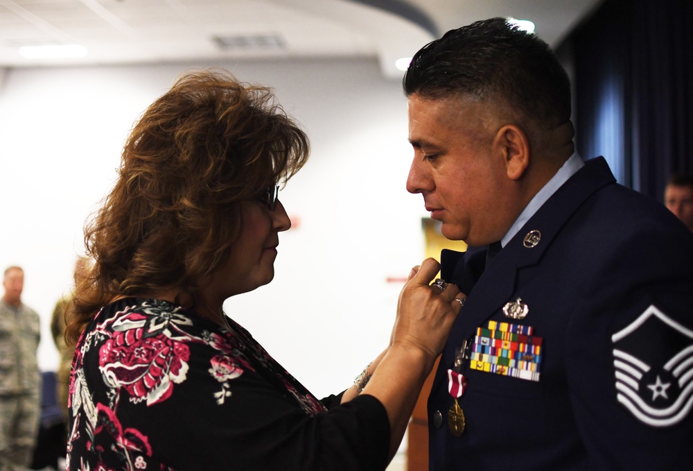 Master Sgt. Bryan Sanchez's wife, Tina Sanchez pins his retirement pin on his lapel