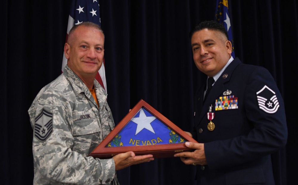 Senior Master Sgt. Tregg Jackson presents the a Nevada state flag to Master Sgt. Bryan Sanchez