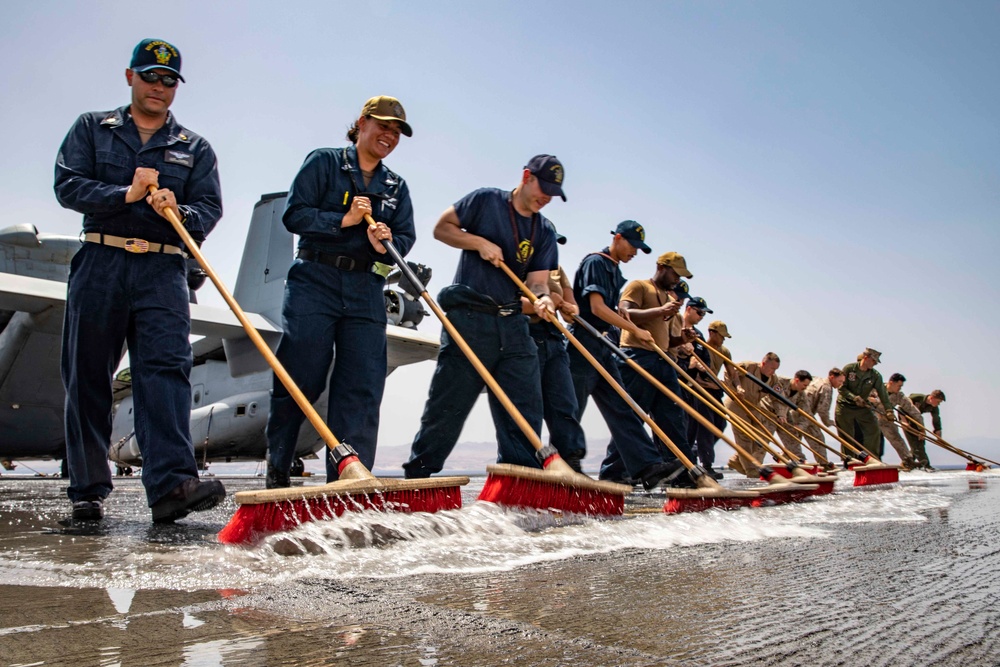 Sailors and Marines wash the flight deck