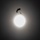 A silhouetted parachutist with a deployed canopy is captured against a large, bright, overexposed celestial body — likely the sun — set against a hazy grey sky. The strong backlighting renders all subjects as dark silhouettes, creating a dramatic high-contrast composition. The image appears to be a deliberate artistic or documentary photograph emphasizing scale and atmosphere.