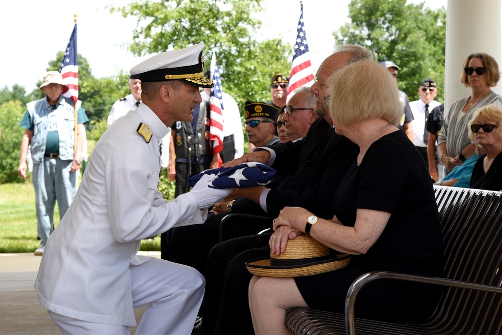 Rear Adm. John Schommer presents a folded flag to a nephew of Navy Fireman 1st Class Angelo M. Gabriele.