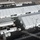 An aerial drone photograph shows a large temporary or semi-permanent facility consisting of multiple white modular/tent-style structures arranged in a compound layout. The facility appears to be a processing or operational center with supporting infrastructure including generators, storage tanks, HVAC units, and vehicle parking areas. The surrounding terrain appears arid, consistent with a desert environment.