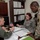 AFMES Joint MWD Lab ensures DoD kennels are meeting the standard Three military personnel are gathered around a desk reviewing documents in what appears to be a military office setting. The group includes one US Air Force member in Airman Battle Uniform (ABU) and one soldier in OCP (Operational Camouflage Pattern) uniform, along with a third individual in olive/green uniform. They appear to be engaged in an administrative or briefing discussion over open binders and paperwork.