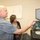 U.S. Transportation Command holds training on TMS prototype at Fort McCoy Two individuals, a man and a woman, are standing at a desk workstation reviewing content on a dual-monitor computer setup. The man is pointing toward one of the screens while the woman observes. The setting appears to be an office or workspace environment with a whiteboard visible in the background.