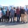 U.S. Transportation Command holds training on TMS prototype at Fort McCoy A group of approximately eleven adults poses for a group photo in a parking lot in front of a fleet of white Ford Transit vans. The setting appears to be a commercial or municipal vehicle lot, likely documenting a vehicle acquisition or organizational event. The group consists of men and women dressed in business-casual attire.