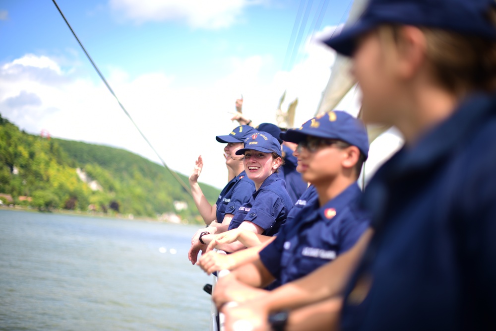 Coast Guard Cadets aboard the U.S. Coast Guard Tall Ship Eagle wave to crowds of people in France