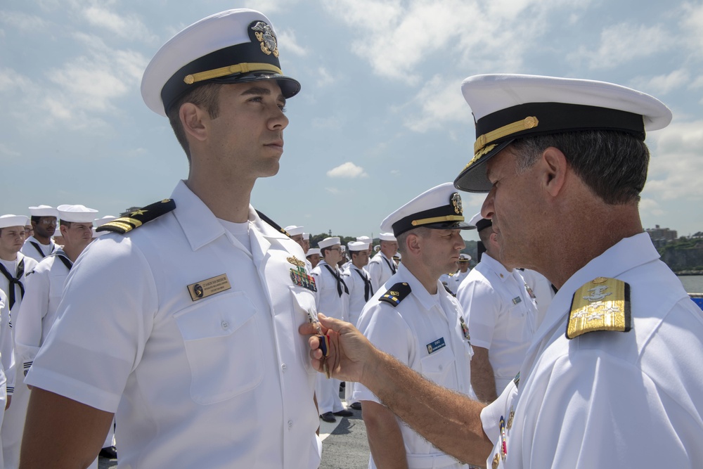 Admiral John Aquilino, Commander, U.S. Pacific Fleet, awards a Sailor during an awards ceremony on USS John S. McCain