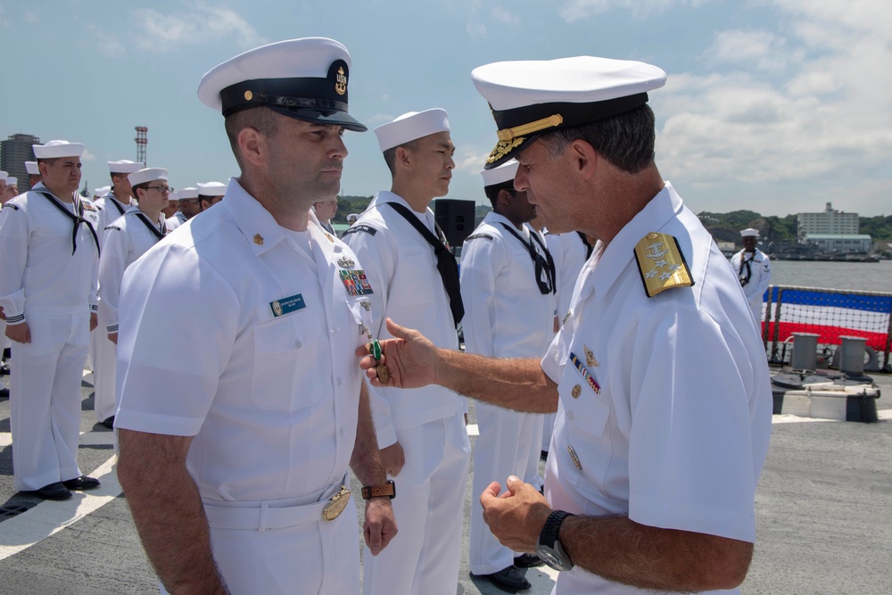 Admiral John Aquilino, Commander, Pacific FLeet, awards a Sailor during an awards ceremony on USS John S. McCain (DDG 56)