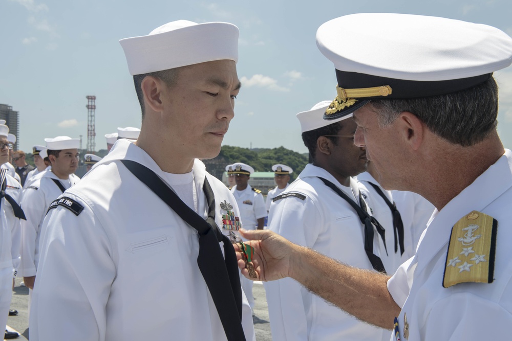 Admiral John Aquilino, Commander, Pacific FLeet, awards a Sailor during an awards ceremony on USS John S. McCain (DDG 56)