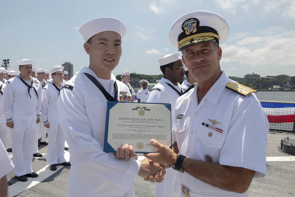 Admiral John Aquilino, Commander, Pacific FLeet, awards a Sailor during an awards ceremony on USS John S. McCain (DDG 56)