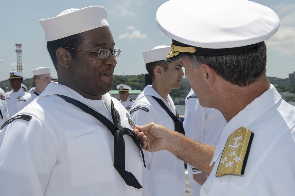 Admiral John Aquilino, Commander, Pacific FLeet, awards a Sailor during an awards ceremony on USS John S. McCain (DDG 56)