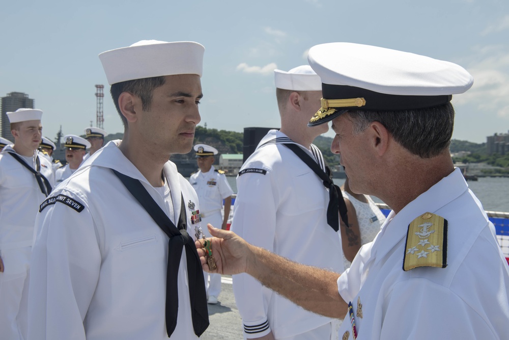 Admiral John Aquilino, Commander, Pacific FLeet, awards a Sailor during an awards ceremony on USS John S. McCain (DDG 56)