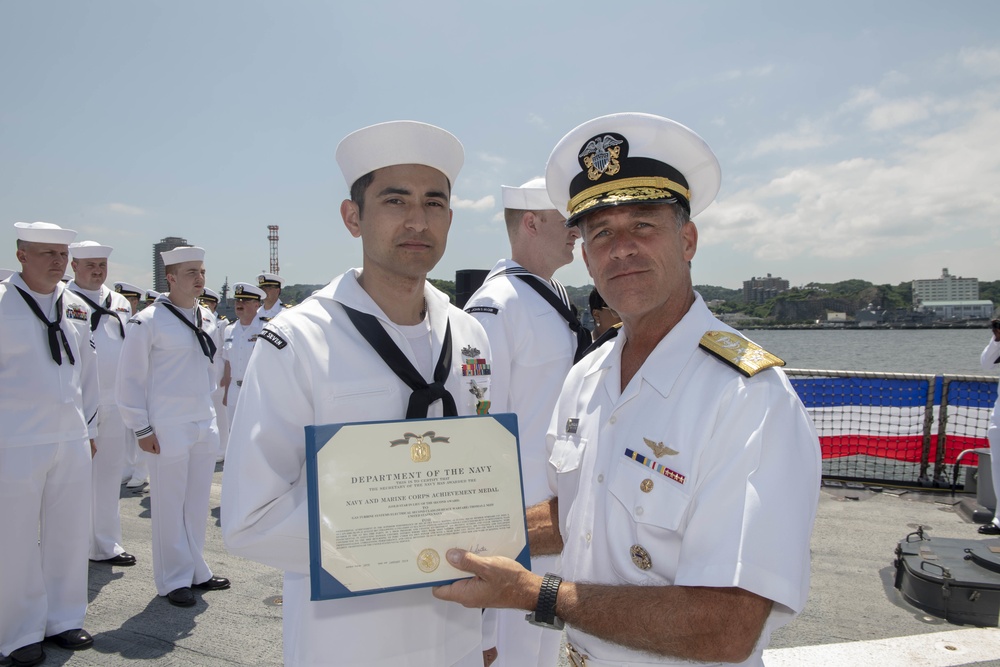 Admiral John Aquilino, Commander, Pacific FLeet, awards a Sailor during an awards ceremony on USS John S. McCain (DDG 56)