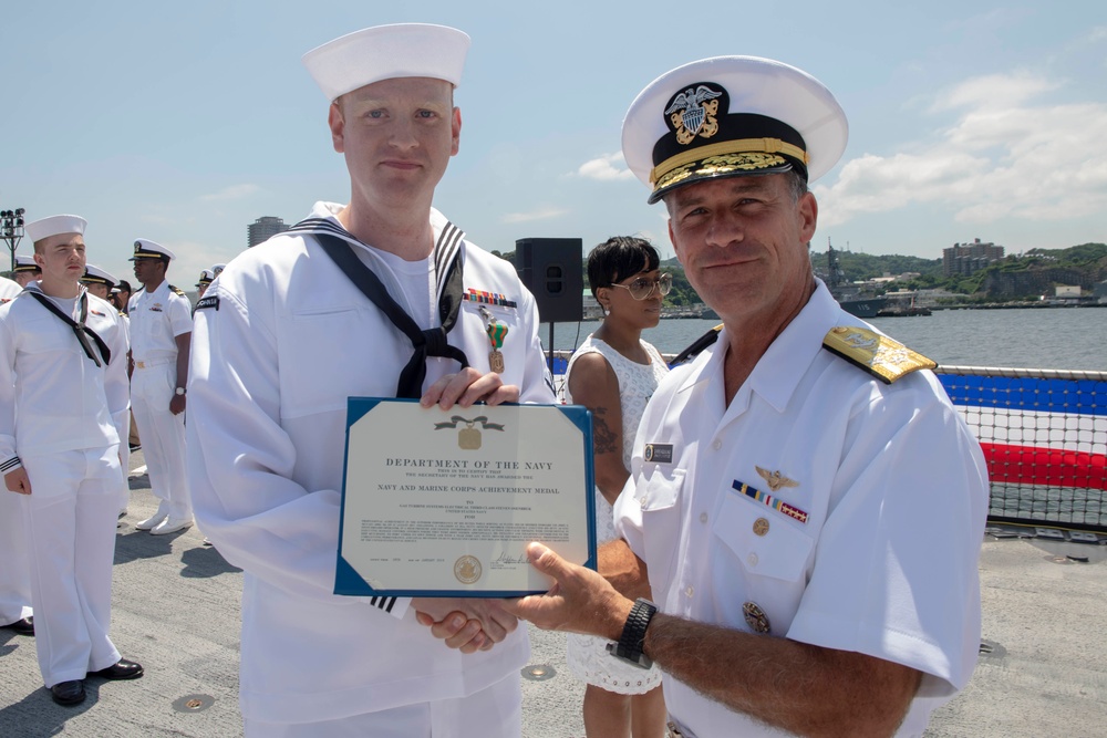 Admiral John Aquilino awards a Sailor during an awards ceremony on USS John S. McCain