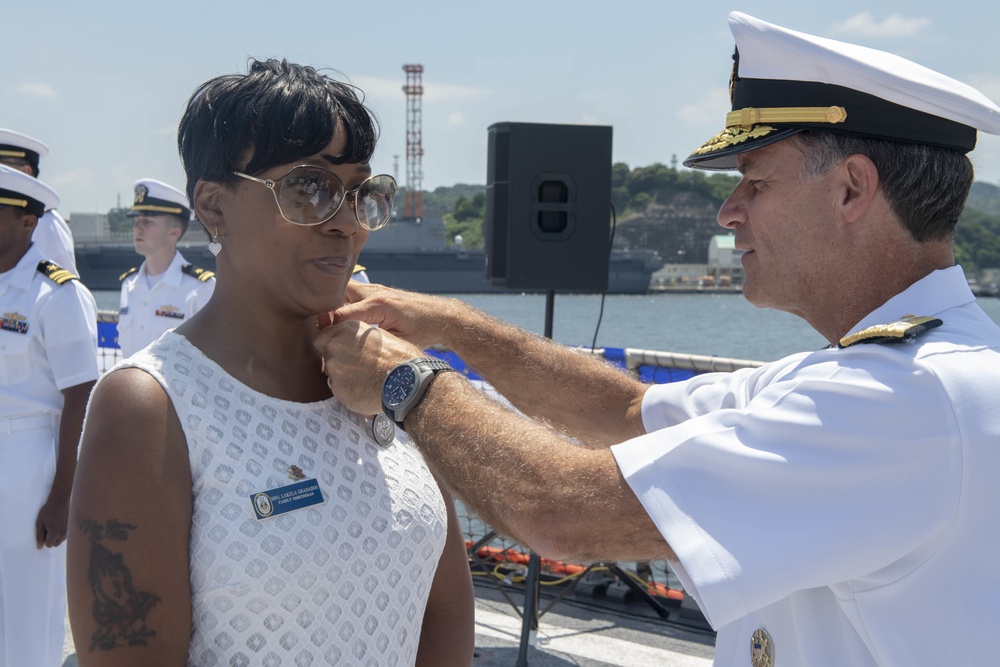 Admiral John Aquilino presents an award to the Ombudsman of USS John S. McCain (DDG 56) during an awards ceremony