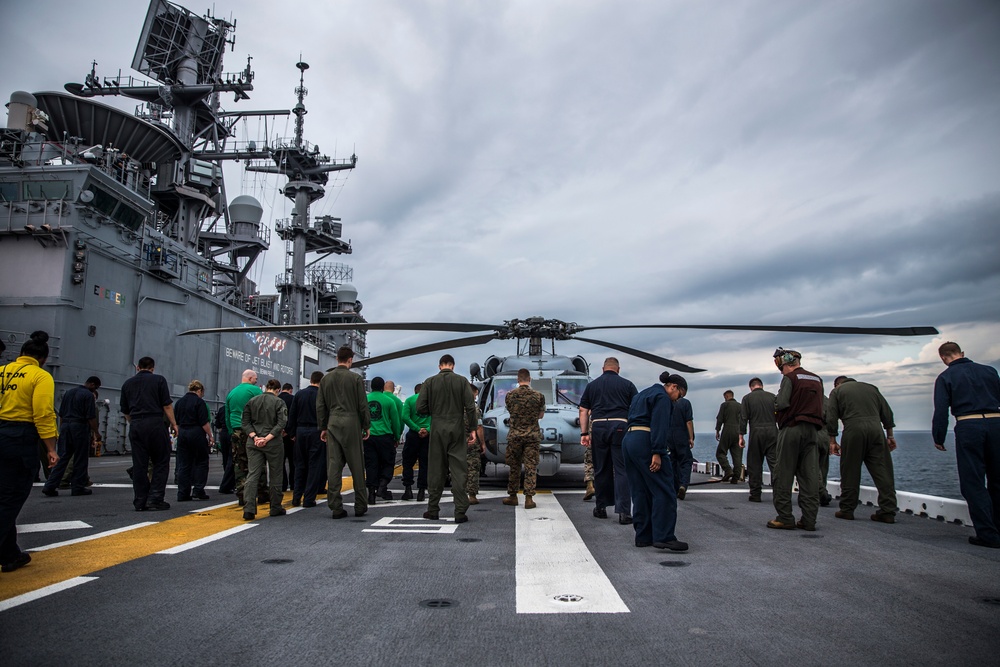 U.S. Marines and Sailors look for foreign object debris aboard the USS Bataan