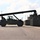 Fort McCoy supports USTRANSCOM's TMS prototype operations A large military reach stacker or container handler vehicle is operating on a paved surface, maneuvering near a row of military shipping containers. The vehicle is painted in olive drab/dark green military coloring and has an extended boom arm reaching toward the containers. An operator is visible in the enclosed cab of the vehicle.