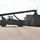 Fort McCoy supports USTRANSCOM's TMS prototype operations A large military reach stacker or container handler, painted in olive drab/dark green, is being operated on a paved surface near a row of shipping containers. The vehicle's extended boom arm is positioned toward stacked containers on the right side of the image. The setting appears to be a military installation or logistics yard based on the equipment color and surrounding infrastructure.