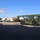 Fort McCoy supports USTRANSCOM's TMS prototype operations The image shows a military-green Kalmar reach stacker/container handler positioned in what appears to be a logistics or intermodal yard. A white semi-truck with a flatbed trailer is visible in the background alongside stacked shipping containers of various colors. The scene suggests a military or government logistics facility engaged in container handling operations.