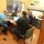 Fort McCoy supports USTRANSCOM's TMS prototype operations Three men are gathered in a small office or workroom, appearing to collaborate or review information together. Two men are seated at a shared desk with a laptop and desktop monitor, while a third man sits at a separate workstation along the wall. The setting appears to be a professional or medical office environment based on the furnishings and layout.