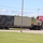 Fort McCoy supports USTRANSCOM's TMS prototype operations A red semi-truck (tractor-trailer) is transporting two large military-style containers on a flatbed trailer along a paved road. One container is painted in a green/brown camouflage pattern, while the other is solid olive/gray. The setting appears to be a military installation or industrial facility based on the surrounding infrastructure.