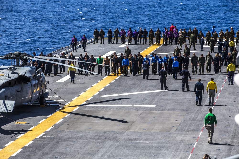 Marines and Sailors Aboard The USS Bataan look for foreign object debris