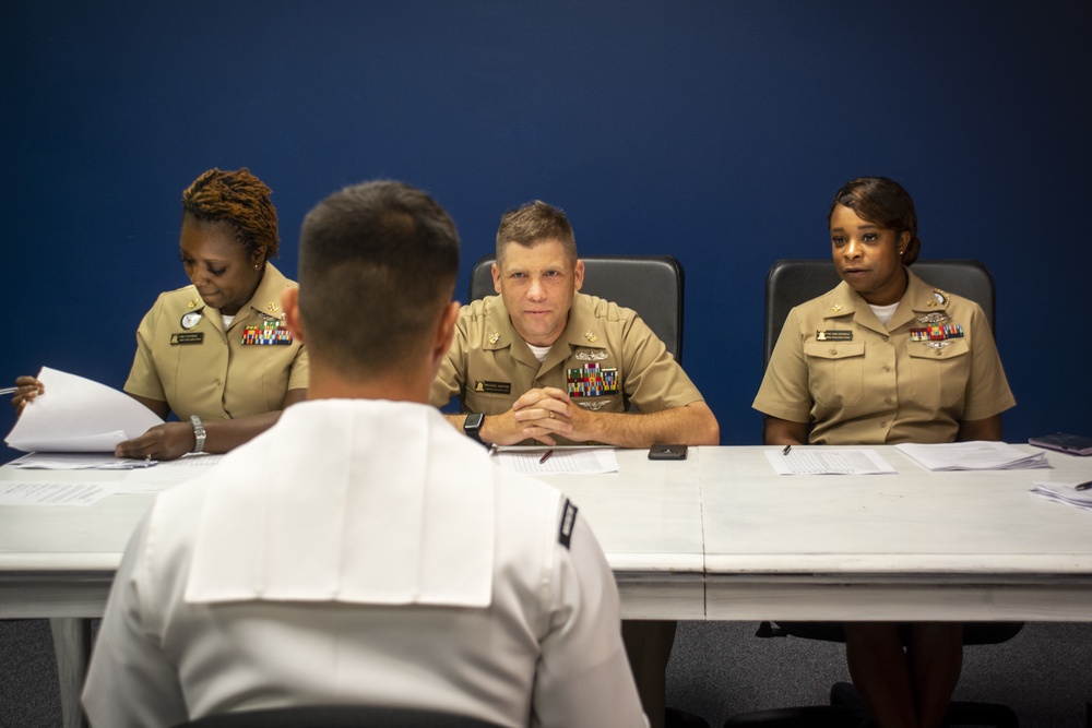 Sailors stand Sailor of the Quarter board at Navy Recruiting District Philadelphia.