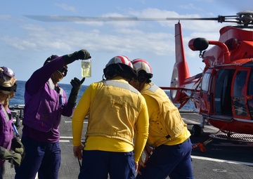 Crewmembers check fuel during "hot gas" operations aboard CGC Bertholf