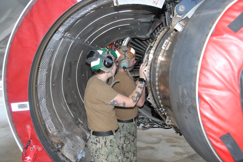 Sailors assigned to Patrol Squadron (VP) 16 inspect a P-8A engine.