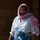 Paralegal training ensures disciplined forces are lethal forces A smiling woman stands in front of a stone or concrete block wall, wearing a white button-up shirt and a red-and-white checkered keffiyeh-style head scarf. A colorful blue and black patterned fabric is tied around her waist. She appears relaxed and cheerful, likely photographed outdoors in bright sunlight.