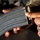 Paralegal training ensures disciplined forces are lethal forces A close-up photograph of a person holding a curved metal rifle magazine loaded with ammunition. The top of the magazine shows brass-cased cartridges visible at the feed lips. The person is wearing a gold ring on their right hand.