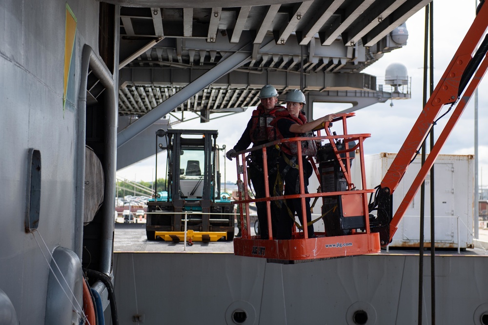 U.S.  Sailors perform maintenance on the side of the aircraft carrier USS John C. Stennis (CVN 74)