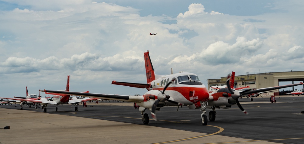 A T-44C Pegasus Taxiing Towards the Runway Aboard NAS Corpus Christi as Another T-44C Flies By