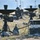The image shows a field deployment of military communications equipment, featuring multiple satellite dish antennas and associated electronic hardware cases arranged across an open grassy area. The equipment appears to be part of a tactical communications or signals intelligence setup, with various cables, tripod-mounted dishes, and ruggedized equipment cases visible. The scene suggests an active military exercise or operational communications node establishment.