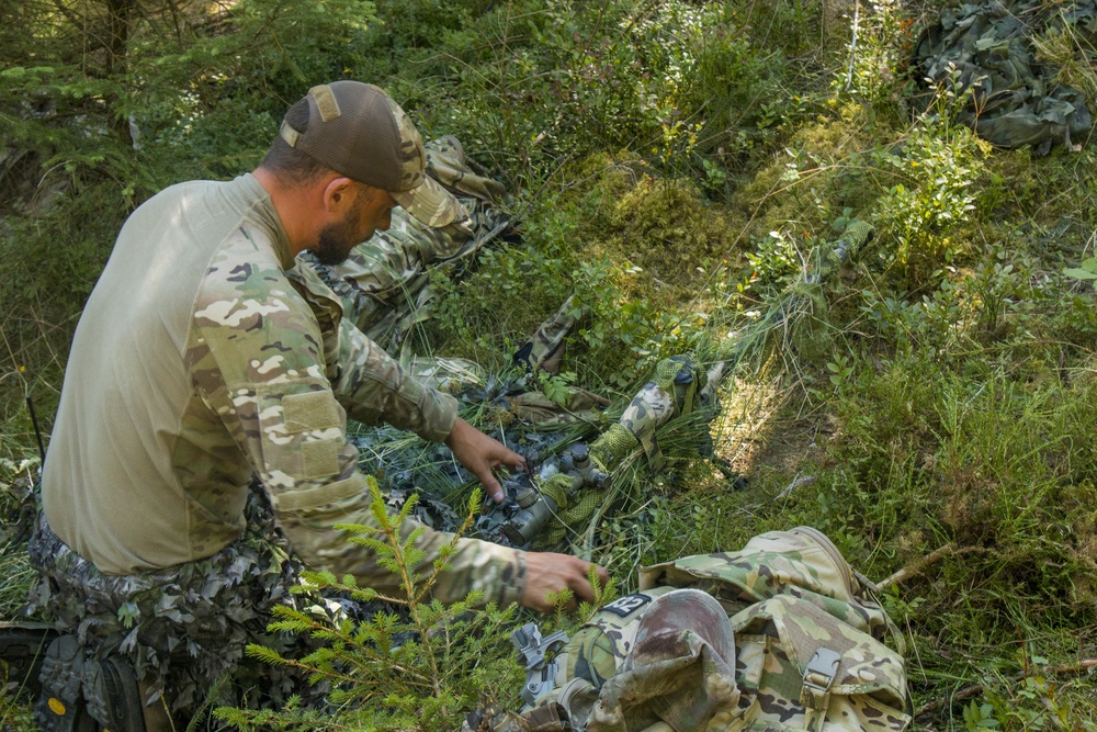 A Polish soldier covers his weapon in camouflage to blend into his surroundings, Grafenwoehr Germany, July 23, 2019.