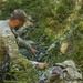 A Polish soldier covers his weapon in camouflage to blend into his surroundings, Grafenwoehr Germany, July 23, 2019.