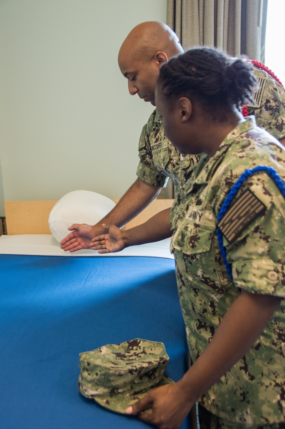 Electronics Technician Chief Jean F. Micourt trains Aviation Ordnanceman Chief LaChanda E. Parker how to properly conduct room, locker and personnel inspection (RLP) at Officer Candidate School (OCS) .