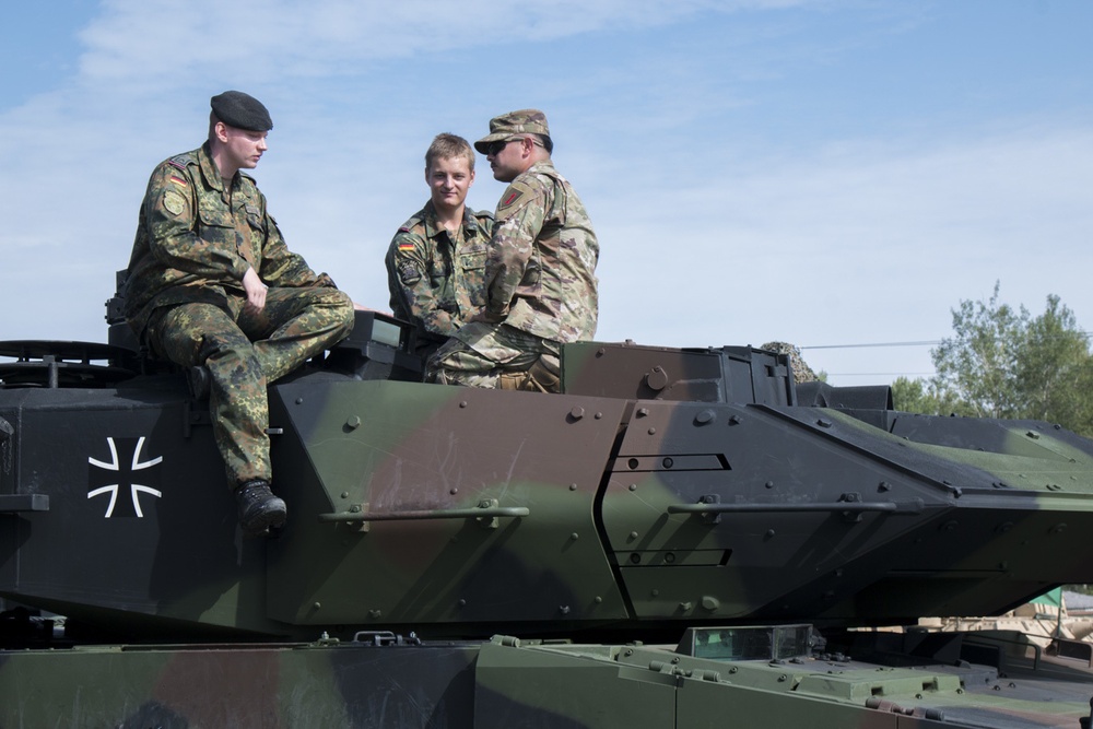 German and American Soldiers sit on top of a tank, enjoying the festivities.