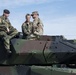 German and American Soldiers sit on top of a tank, enjoying the festivities.