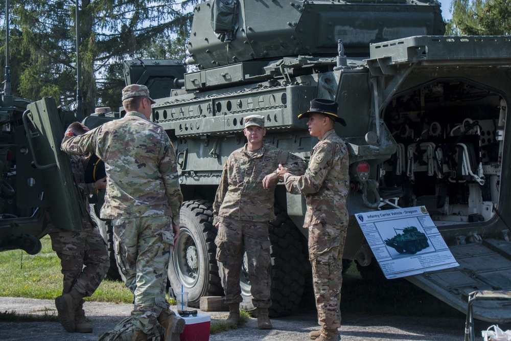 American Soldiers assigned to 2CR, 7th ATC prepare for the festivities as they stand next to their vehicle, the Infantry Carrier Dragoon.