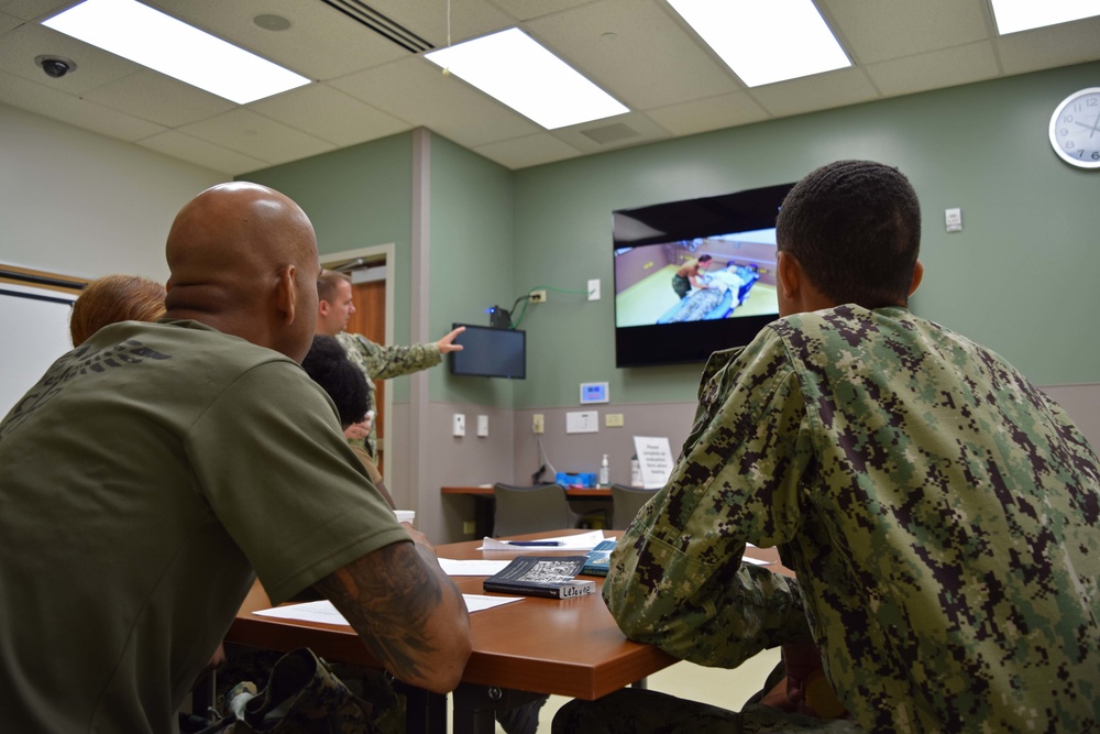 Students receive a de-brief during Sick Call Screeners Simulation Course