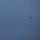 Marine F-35B Lightning II fighter aircraft complete GAU-22 cannon, ordnance hot reload exercise in Indo-Pacific Region A single military jet aircraft is visible in flight against a hazy, overcast blue-grey sky. The aircraft appears small and distant, positioned in the right-center portion of the frame. The overall image is low contrast due to atmospheric haze and dim lighting conditions.