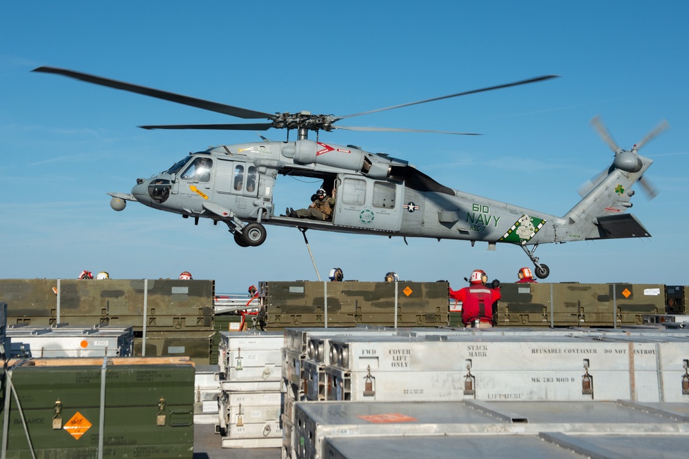 An MH-60S Sea Hawk lifts ammunition from the flight deck