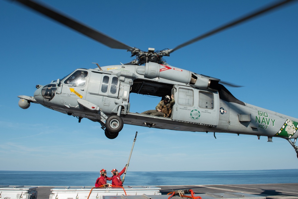 An MH-60S Sea Hawk prepares to lift ammunition from the flight deck