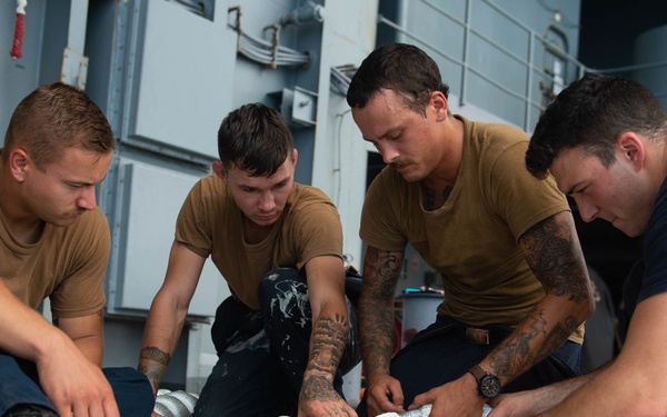 U.S. Sailors splice an eye into mooring lines.