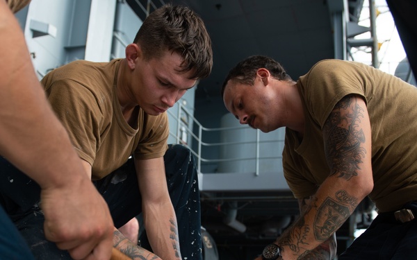 U.S. Sailors splice an eye into mooring lines.