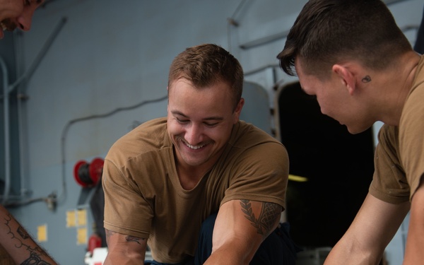 U.S. Sailors splice an eye into mooring lines.