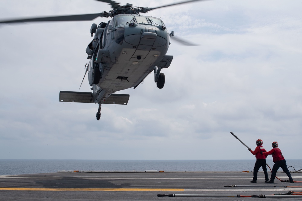 U.S. Sailors prepare to attach ammunition to an MH-60S Sea Hawk