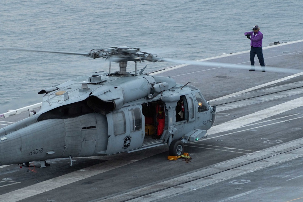 U.S. Sailor signals to fuel an aircraft