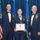Airman Leadership School distinguished graduate Three United States Air Force personnel pose for a formal photograph at what appears to be an Airman Leadership School graduation ceremony. The central figure, a female airman, holds a diploma from the United States Air Force Airman Leadership School and wears a graduation medal. She is flanked by two senior enlisted members (Chief Master Sergeants) in dress blues with bow ties.